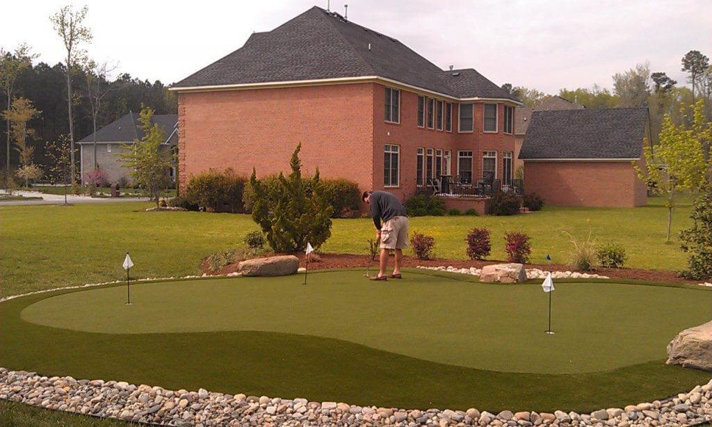Golfer practicing on an artificial backyard putting green