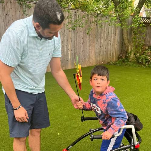 father and son playing with pinwheel on artificial grass